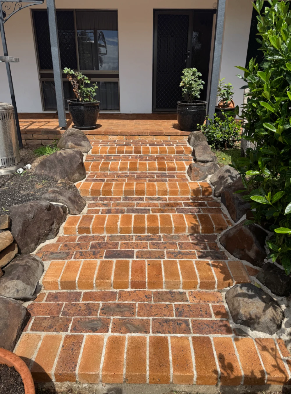 Freshly washed brick entrance steps bordered by rocks and plants