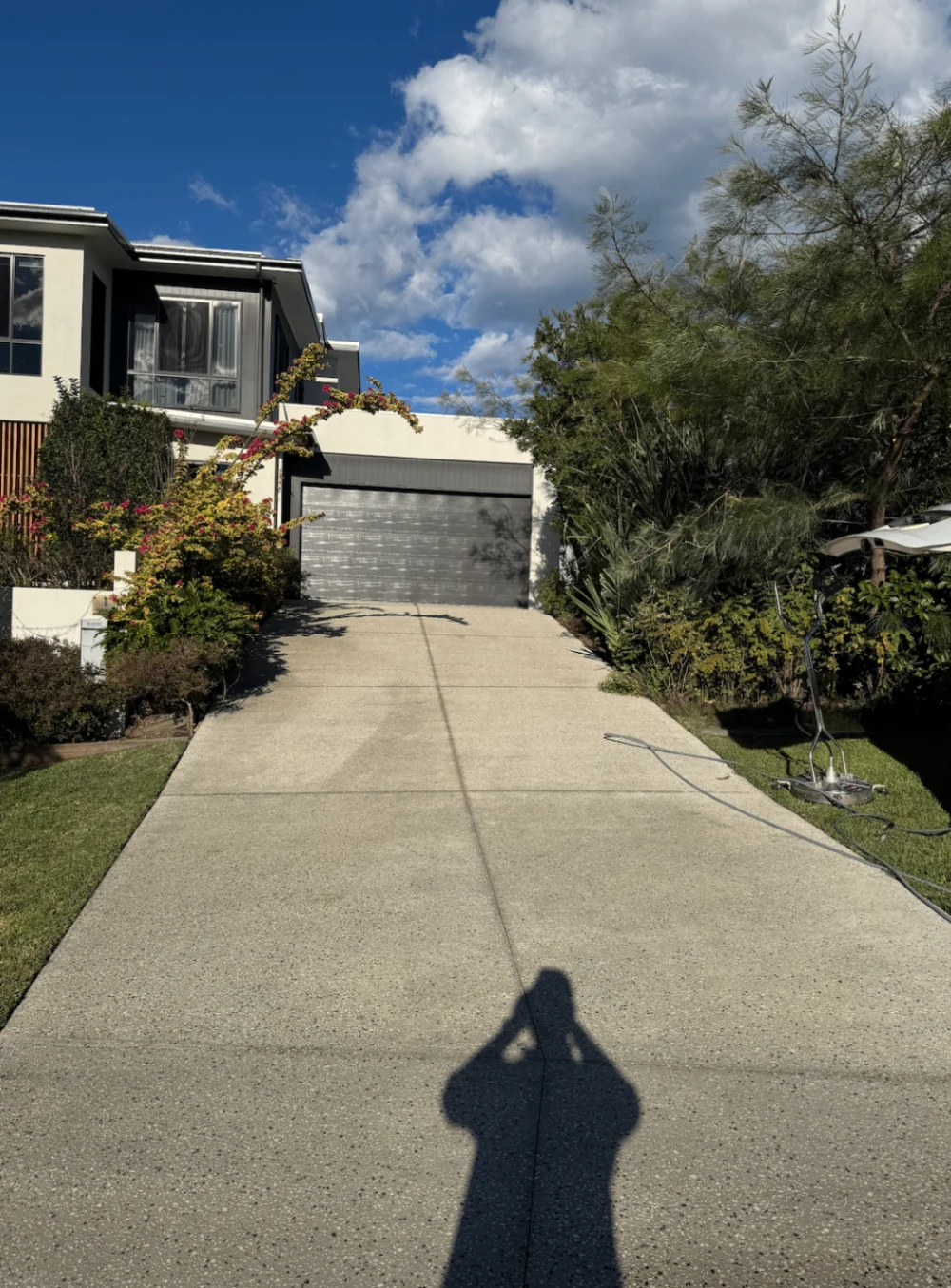 Clean sloping driveway leading to a garage beneath a bright sky